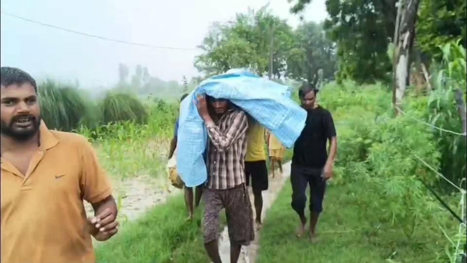 वीडियो गोंडा के बाढ़ ग्रस्त गांव अइली मांझा के गांव बाबूराम पुरवा गांव का है, जहां बीमार एक बुजुर्ग को पहले चारपाई बाद में नाव से ले जाते हुए कुछ लोग नजर आ रहे हैँ, इस गांव की स्थिति ये है की यहाँ 4 किलोमीटर में गांव आने जाने का जो कच्चा रास्ता है वो बारिश में इतना खराब हो चुका है, उसपर पैदल चलना भी खतरे से खाली नहीं है ऐसे में गांव वाले जिस मजबूरी से जूझ रहे हैँ, उसकी बानगी है ये तस्वीर