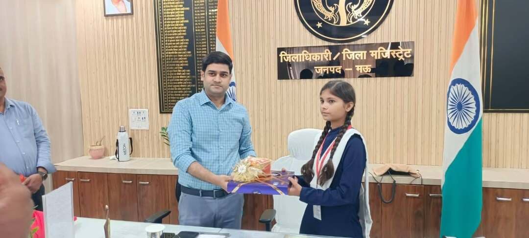 उत्तर प्रदेश के मऊ में मिशन शक्ति अभियान के तहत कस्तूरबा गांधी आवासीय बालिका विद्यालय, कोपागंज की कक्षा 10 की छात्रा अंशिका को एक दिन के लिए जिलाधिकारी बनाया गया। इस दौरान अंशिका ने जिलाधिकारी की कुर्सी पर बैठकर जनसुनवाई की और फरियादियों की समस्याओं को गंभीरता से सुना। उन्होंने संबंधित अधिकारियों को नियमानुसार शिकायतों के निस्तारण के लिए आवश्यक कार्रवाई करने के निर्देश दिए। जिलाधिकारी आनंद वर्धन ने अंशिका का पुष्पगुच्छ देकर स्वागत किया और उन्हें प्रशासनिक कार्यप्रणाली तथा जनसमस्याओं के समाधान की प्रक्रिया से अवगत कराया। शारदीय नवरात्र के अवसर पर आयोजित इस पहल का उद्देश्य बालिकाओं में नेतृत्व क्षमता, आत्मविश्वास और प्रशासनिक व्यवस्था के प्रति जागरूकता बढ़ाना है। मिशन शक्ति के माध्यम से बालिकाओं को आगे बढ़ने और अपनी क्षमताओं को पहचानने के लिए प्रोत्साहित किया जा रहा है।